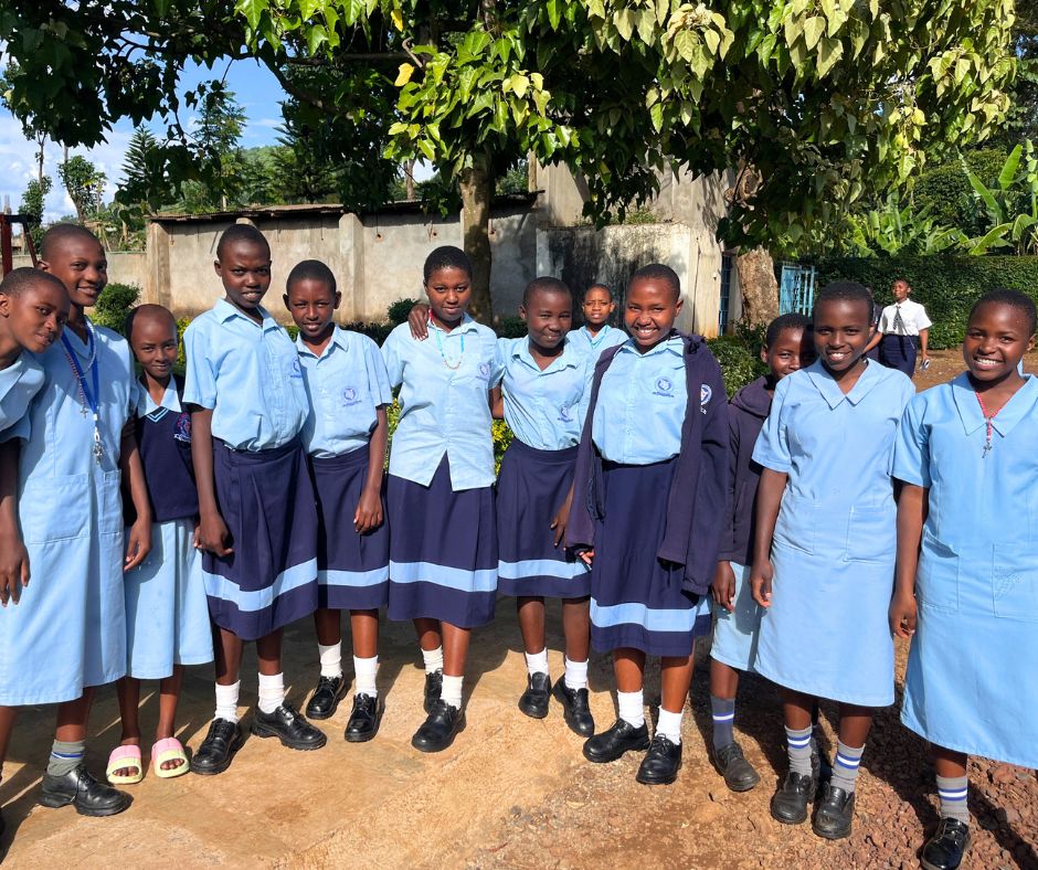 Photo of girls in light blue uniforms with their arms around each other smiling